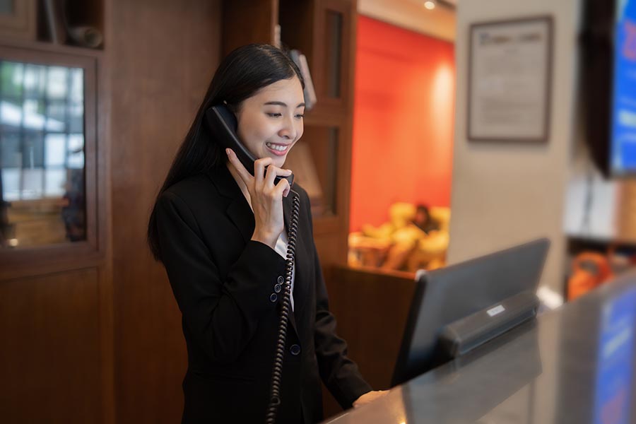 Contact - Hotel Owner Makes a Call at Reception Desk in High End Hotel